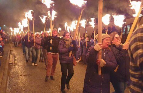 A group of people with torches walking down a street.