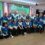 Group of people in matching team shirts posing for a photo indoors.