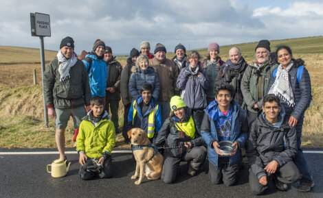 A diverse group of people and a dog posing for a photo by a sign that reads "passing place.
