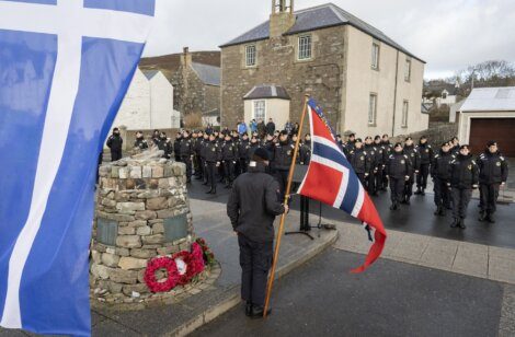 Police officers attending a commemorative ceremony with flags displayed.