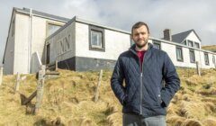 A man standing in front of a building with the word "inn" on the facade.