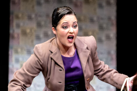 A woman with a surprised expression, speaking on stage.