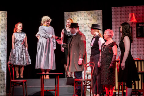 A theatrical performance with actors in vintage costumes on a stage set representing a bar.
