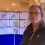 Woman in uniform standing in front of informational posters about a proposed fish holm expansion.
