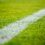 Close-up of a white boundary line on a lush green soccer field.