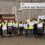 Group of workers in safety vests holding "unite" signs in front of sullom voe terminal entrance.