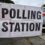 A white banner with bold black text reads "POLLING STATION" attached to a metal fence outside a building. A parked car is visible in the background.
