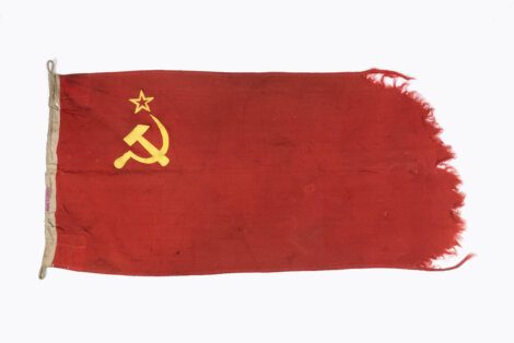 A tattered red flag featuring a yellow hammer and sickle symbol with a star above it, which is the emblem of the former Soviet Union.