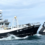 Two fishing boats, H-90 and H-360, navigate through the ocean under a cloudy sky.