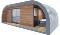 A modern, curved tiny house with wood paneling, sliding glass doors, and a small set of steps leading to an entrance. The interior is partially visible.