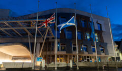 Flags at half-mast outside a modern building at dusk.