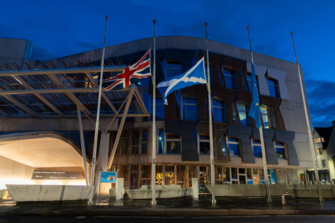 Flags at half-mast outside a modern building at dusk.