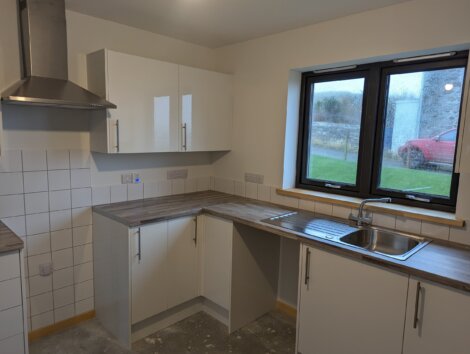 Modern kitchen with white cabinets, a stainless steel range hood, and a sink under a window.
