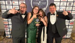 Four people in formal attire celebrate with an award at the Scottish Fish & Chip Awards backdrop.