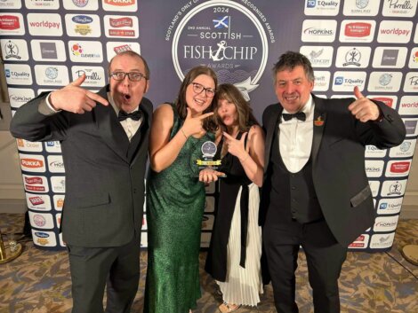 Four people in formal attire celebrate with an award at the Scottish Fish & Chip Awards backdrop.