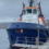 A large blue and white boat named "Dunter" is docked at a pier on a cloudy day.