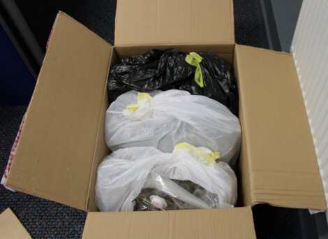 An open cardboard box containing plastic bags filled with various items.
