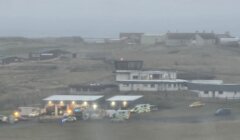 Emergency vehicles gathered near a building in a foggy landscape.