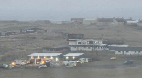 Emergency vehicles gathered near a building in a foggy landscape.
