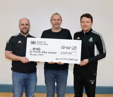 Three men holding a large check from Lerwick Celtic Football Club for £1400, payable to MIND, dated 13-01-25.