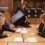 A woman empties a ballot box onto a table while four other people sort through the papers.