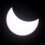 A partial solar eclipse with the moon covering a large portion of the sun, leaving a crescent-shaped bright area against a dark background.