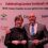 Two people in formal attire smiling and holding glass awards in front of a backdrop with sponsor logos at a Lantra Scotland's ALBAS event.