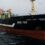 Large black and red fishing vessel "HELEN MARY" with identification number ROS 785 sails on overcast sea, accompanied by a small boat nearby.