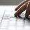 Close-up of a person's fingers typing on a laptop keyboard.
