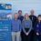 Six people stand smiling beside a banner for the Brae Rural Energy Hub, which promotes climate-conscious community action in Shetland.