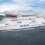 A large white NorthLink ferry with blue accents sails on calm water under a cloudy sky.