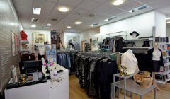 A clothing store interior with racks of clothes, shelves, a counter with a register, and mannequins displaying outfits and accessories.