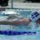 Swimmer in a cap and goggles performing the butterfly stroke in a swimming pool during a competition.