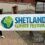 Two people stand outside holding a banner that reads "Shetland Climate Festival" with an earth graphic on it.