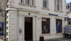 The exterior of a Royal Bank of Scotland branch, showing the entrance and several large street-facing windows.