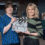 Two women stand indoors holding a clapperboard labeled "Shetland" in a room with office furniture and shelves in the background.